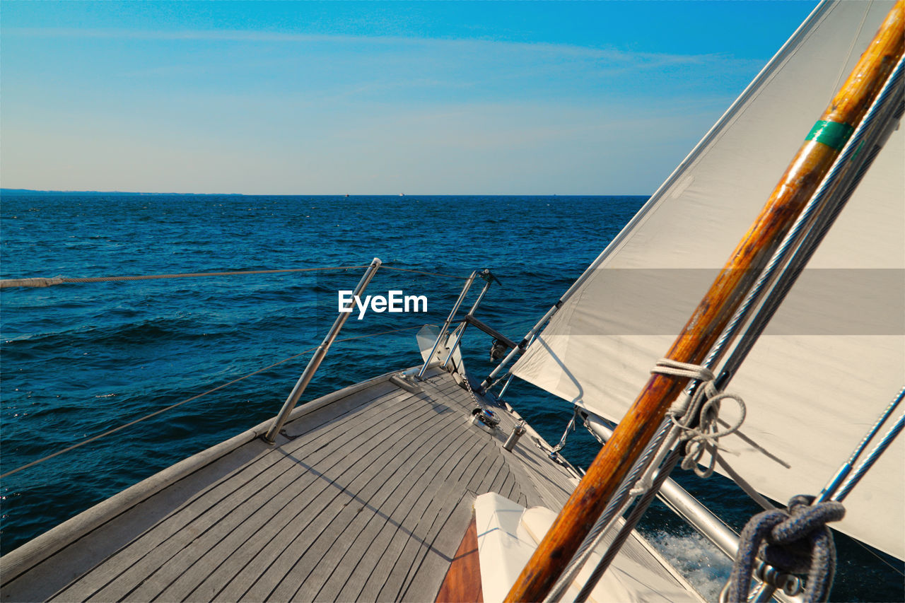 Sailboat sailing on sea against blue sky