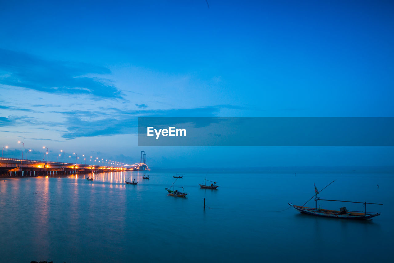 Boats moored on sea against blue sky