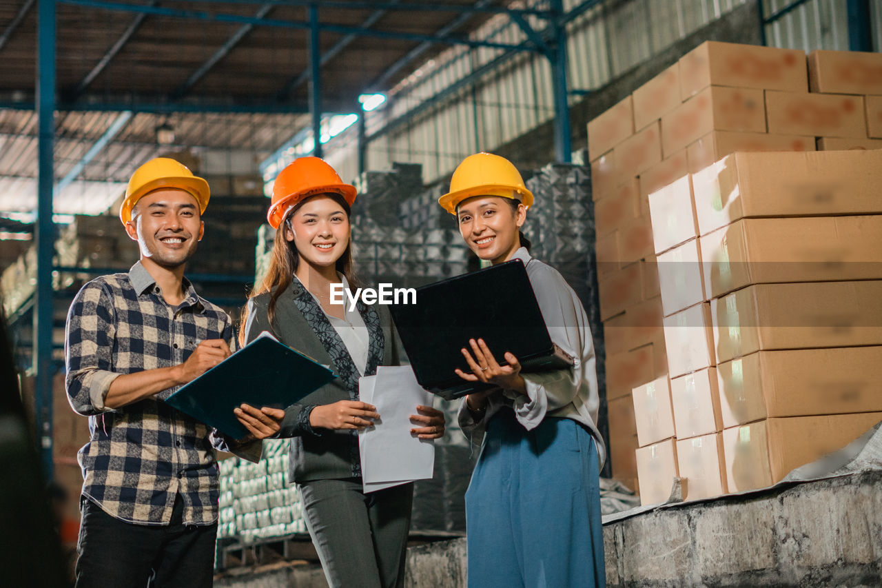 portrait of smiling young woman standing against building