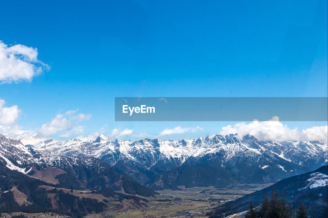 Scenic view of snow covered mountains against blue sky