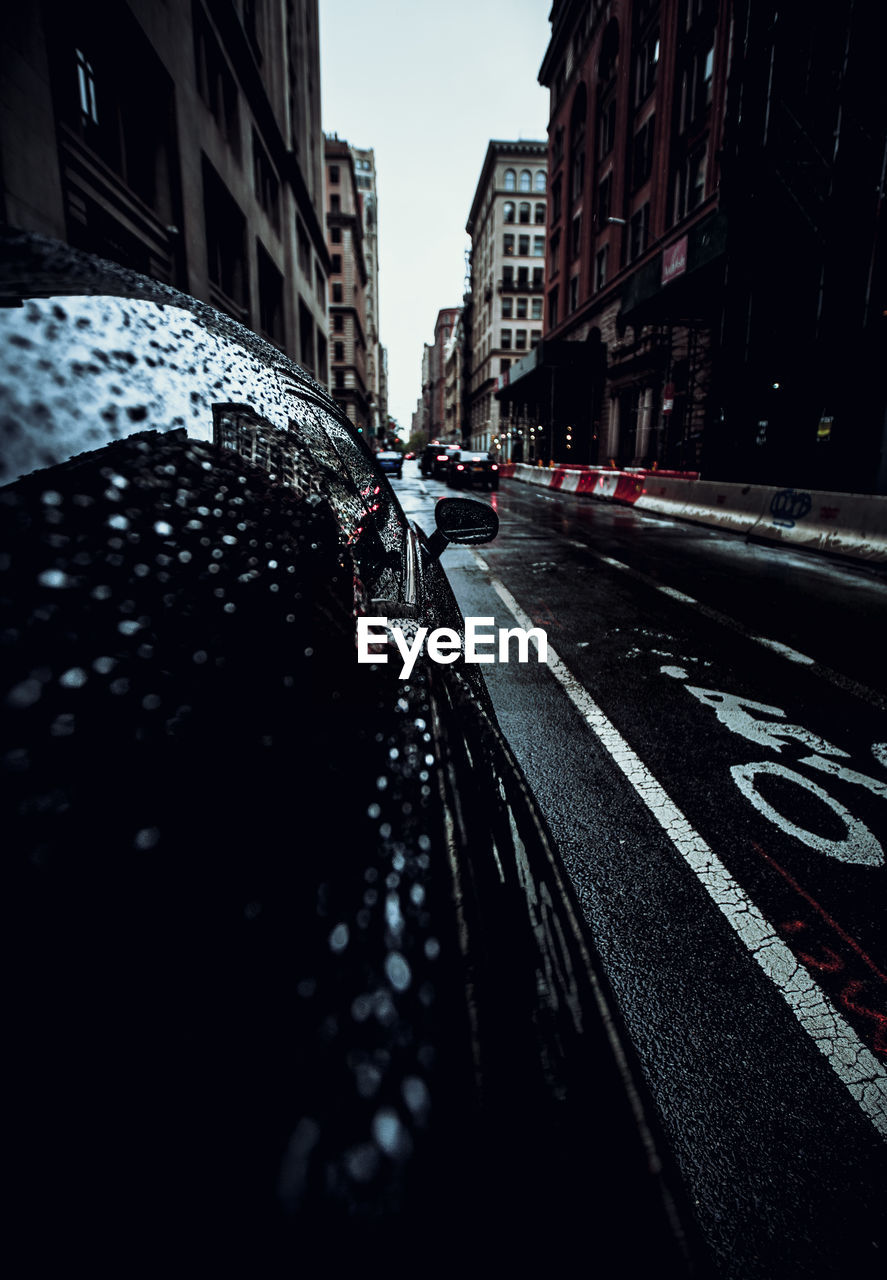 Surface level of wet street amidst buildings in city