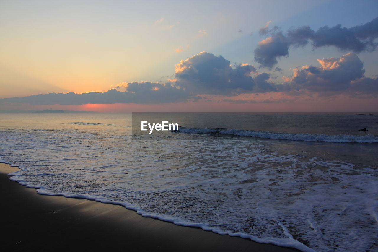 Scenic view of sea against cloudy sky during sunset