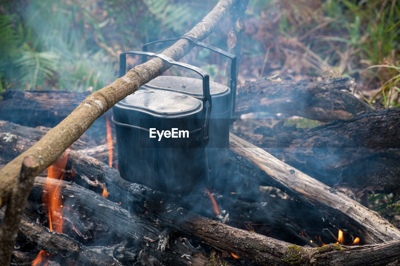 High angle view of food in containers cooking over campfire