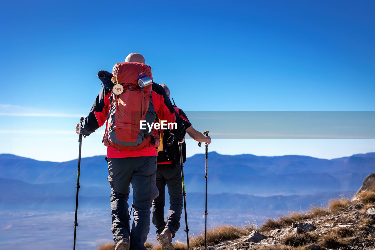 Two hikers reach the summit of mountains in abruzzo, italy.