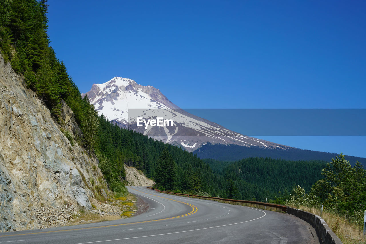 Road amidst mountains against clear blue sky