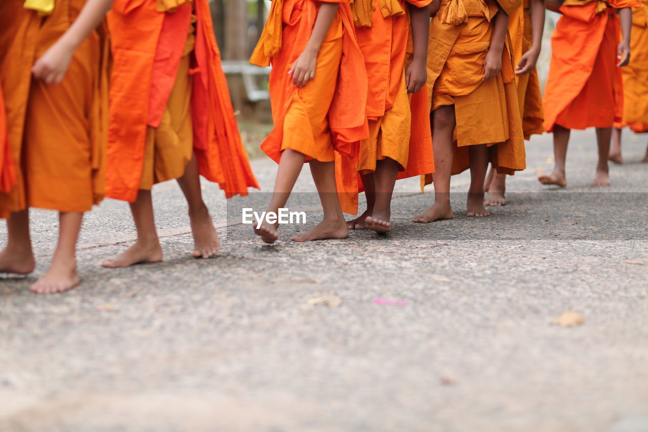 Low section of monks walking on footpath