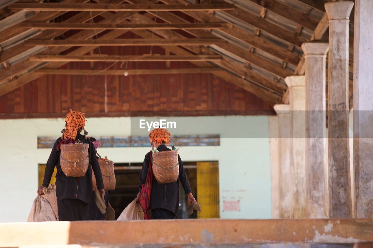 Rear view of women carrying baskets in building