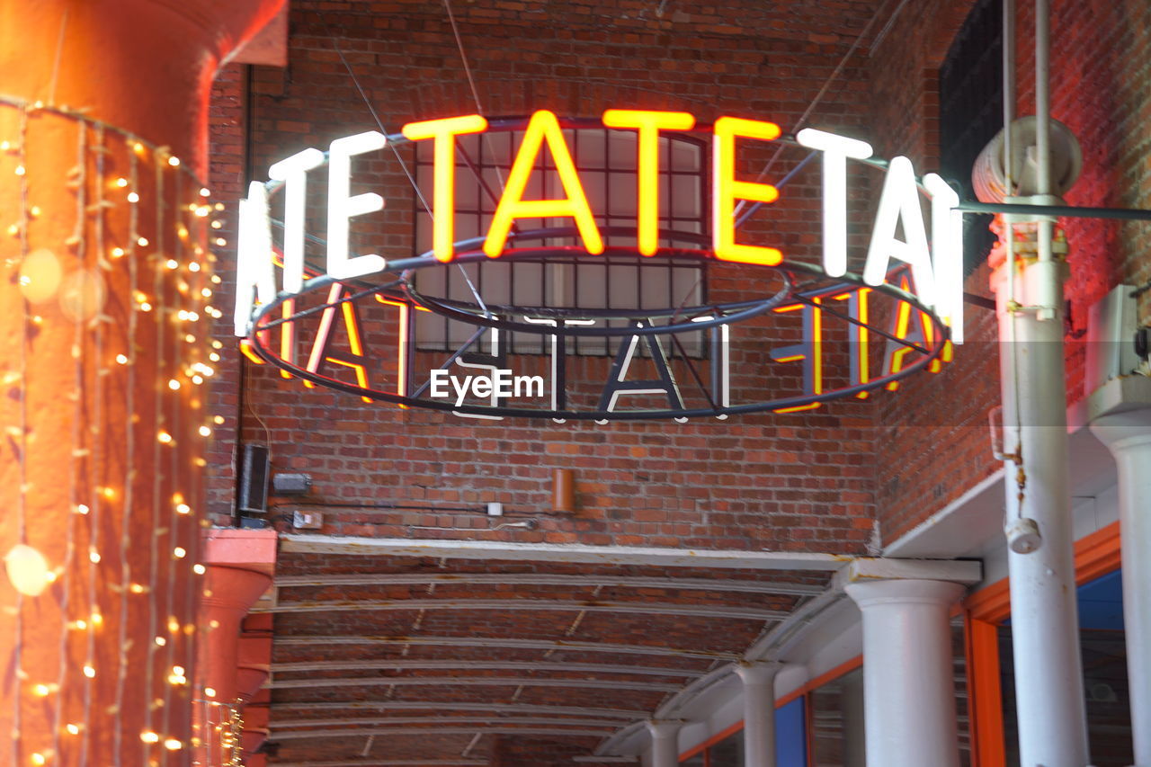 LOW ANGLE VIEW OF ILLUMINATED TEXT ON BUILDINGS AT NIGHT