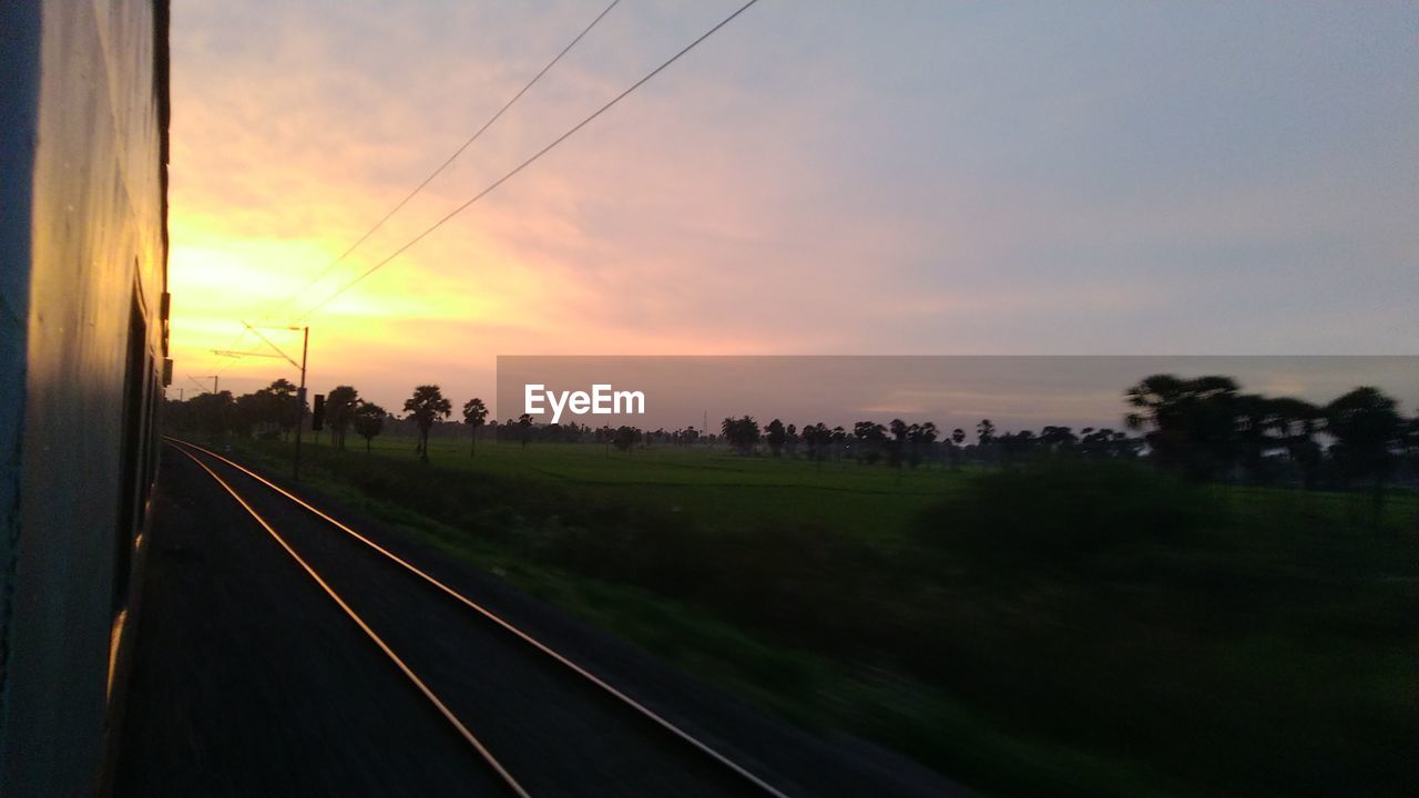 VIEW OF RAILROAD TRACKS AGAINST SKY DURING SUNSET