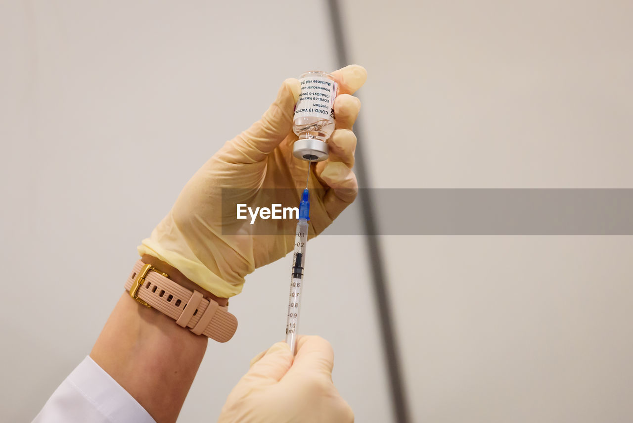 Cropped hand of doctor holding vial and injection at hospital