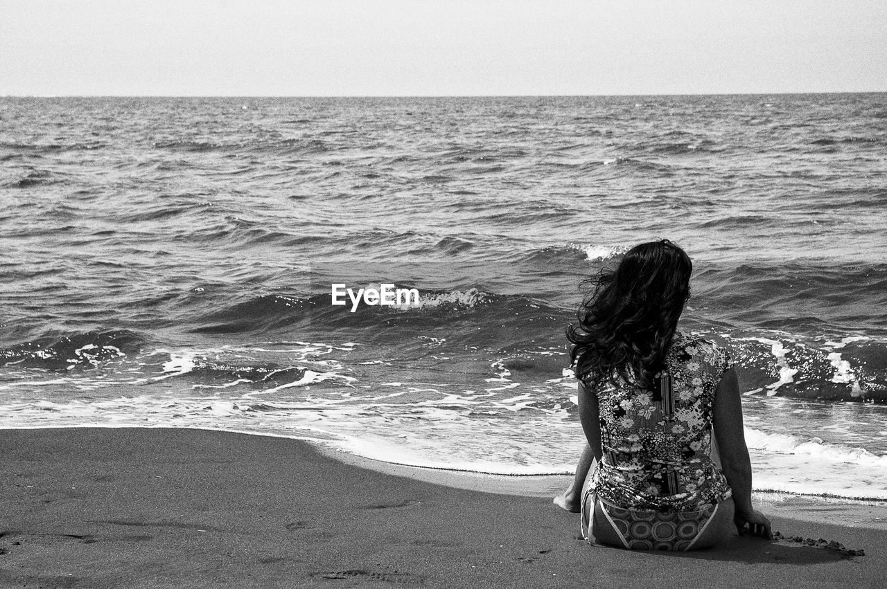 Rear view of woman sitting on beach