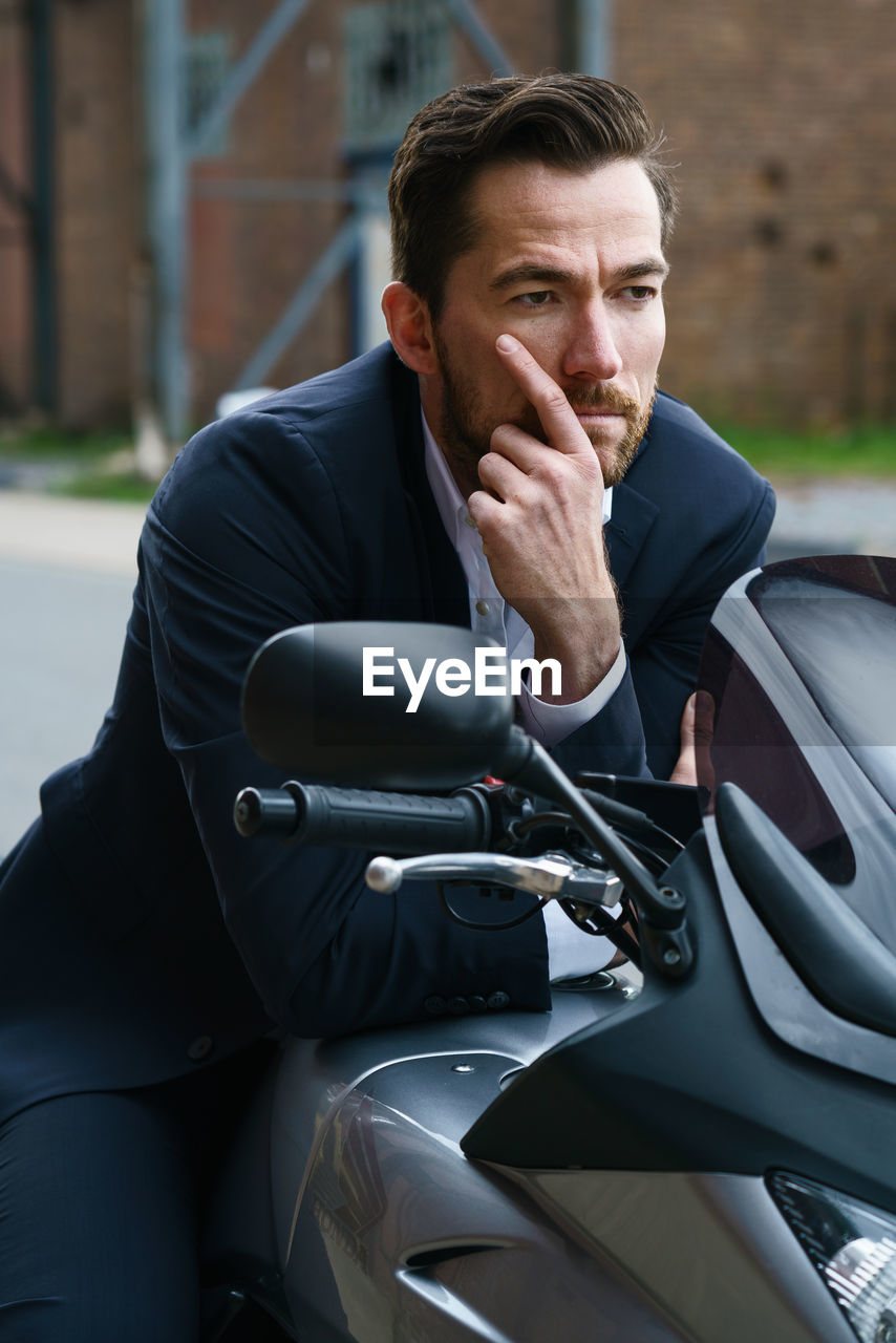 Man looking away while sitting on motorcycle outdoors