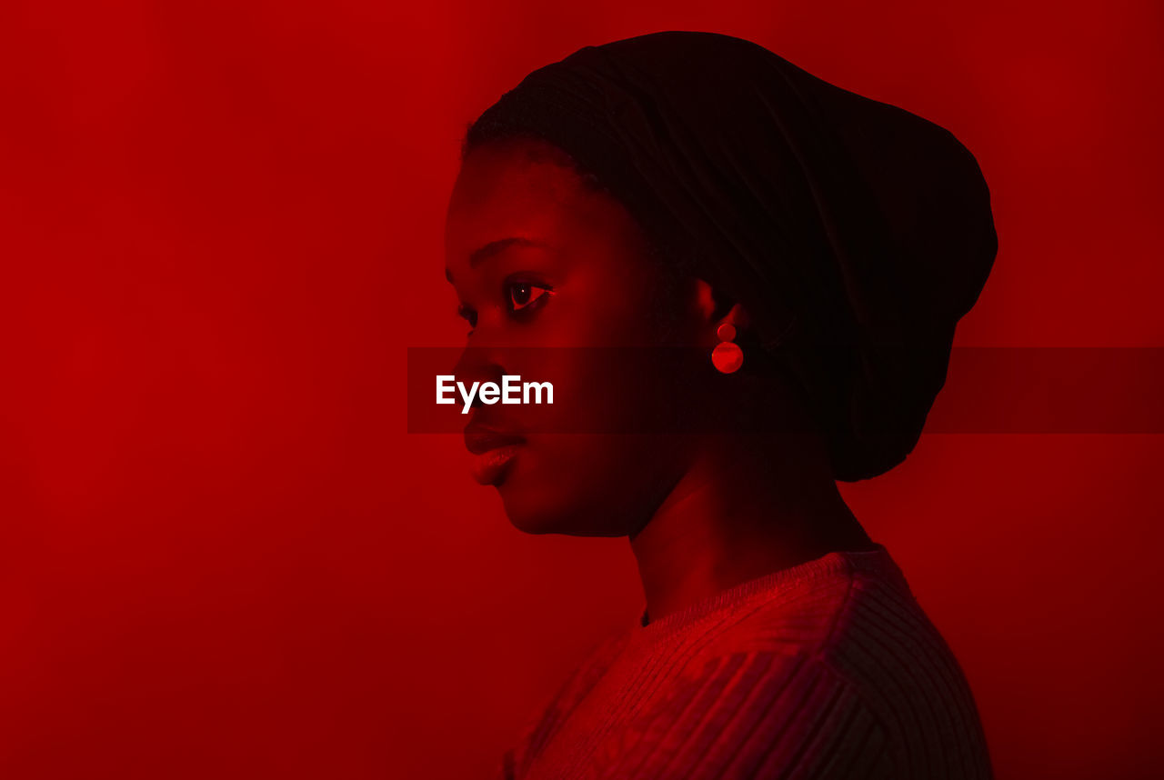 Young woman contemplating in front of red background