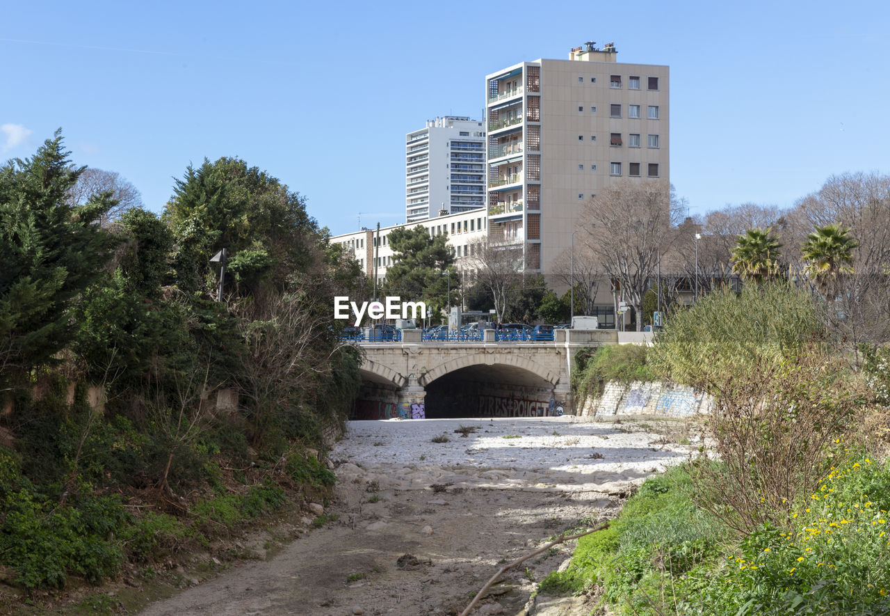 BRIDGE OVER RIVER BY BUILDINGS AGAINST SKY