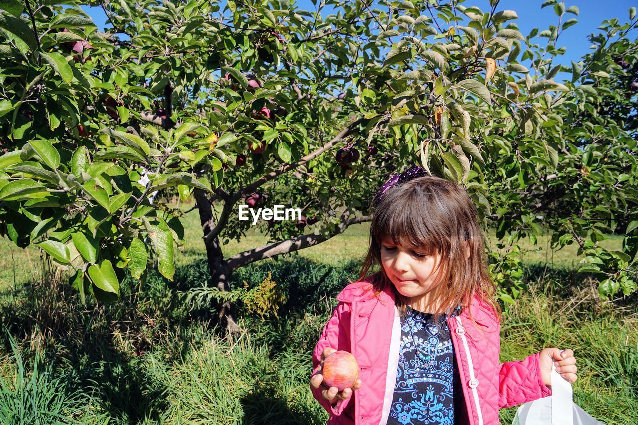 PORTRAIT OF A GIRL STANDING BY PLANTS