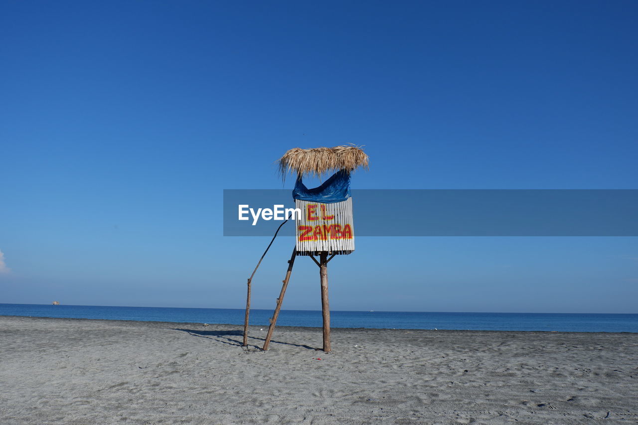 LIFEGUARD HUT ON SHORE AGAINST CLEAR BLUE SKY