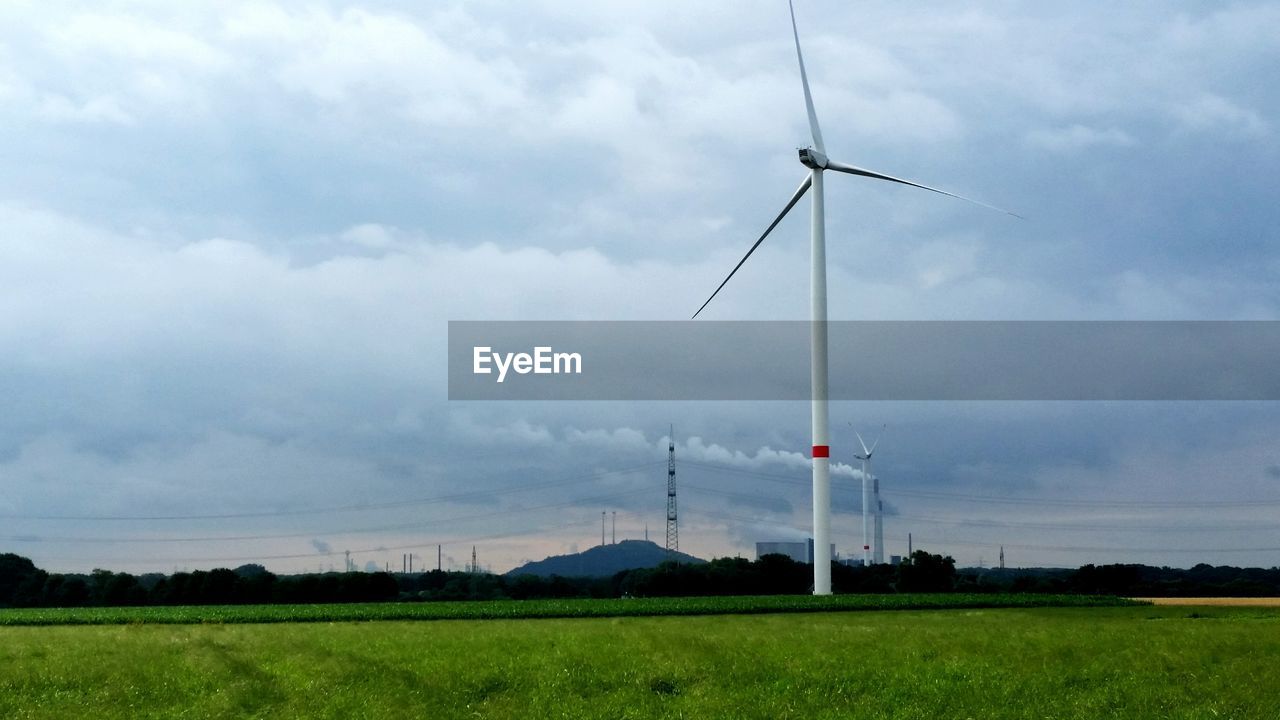 Low angle view of windmills on field against sky