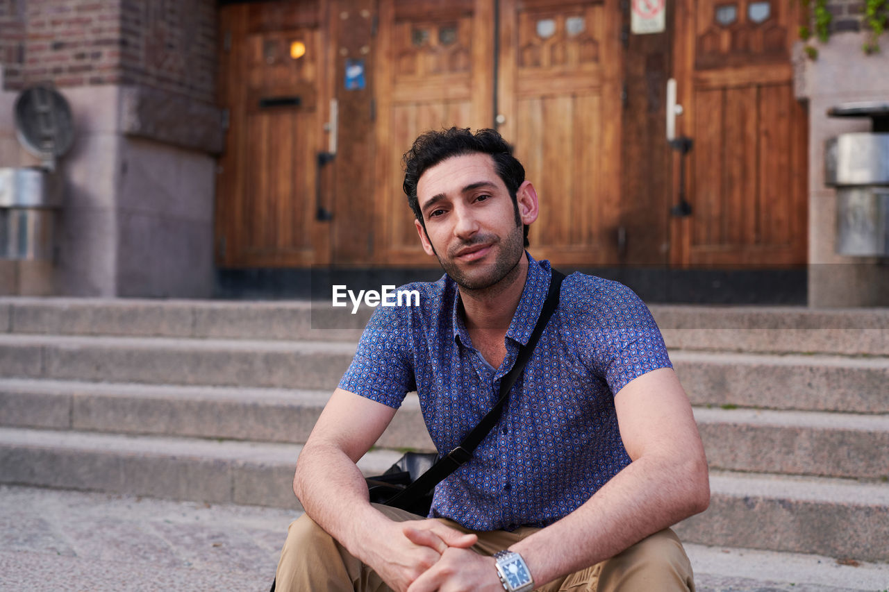 Portrait of confident male student sitting outside language school