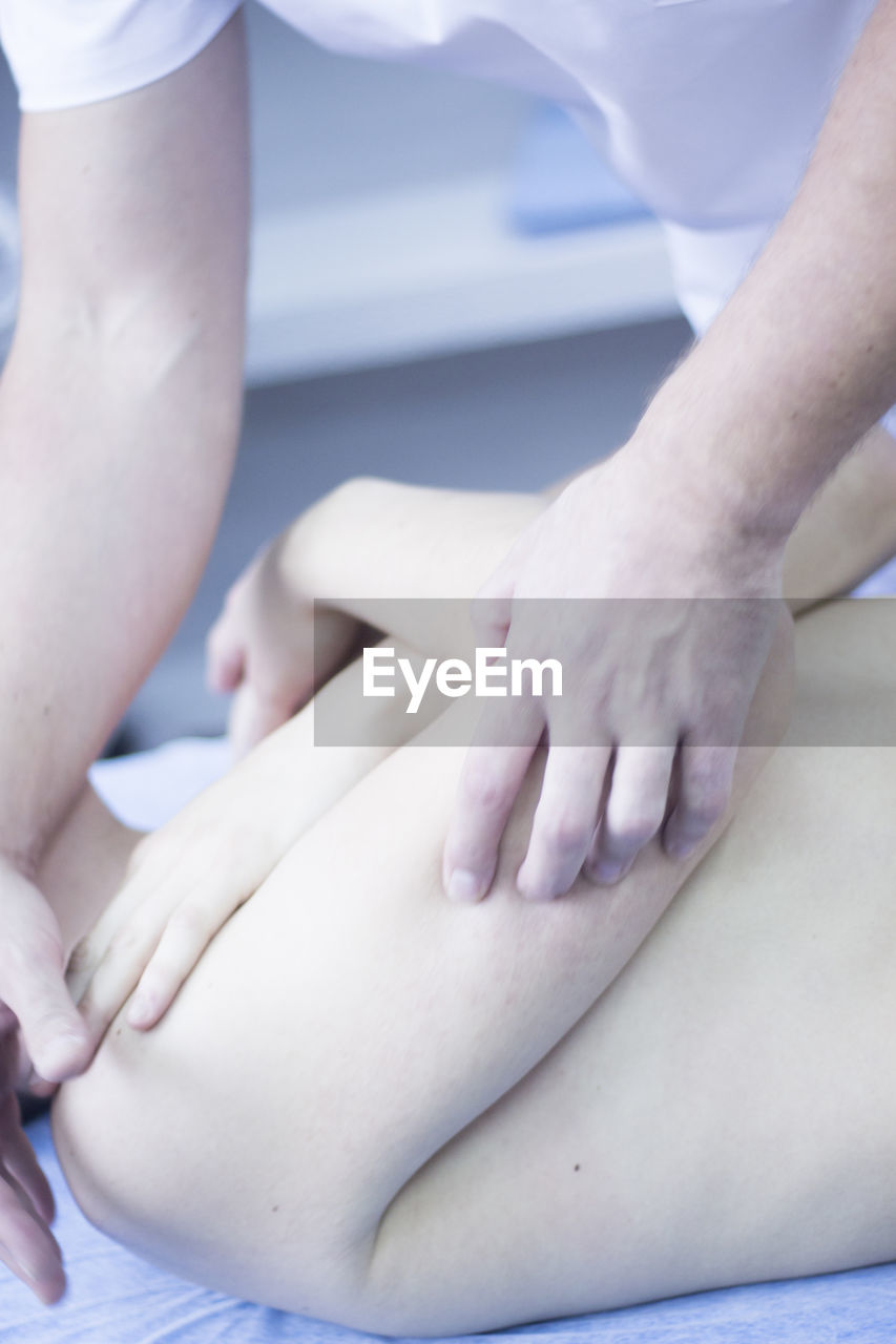 Midsection of physiotherapist treating patient on hospital bed