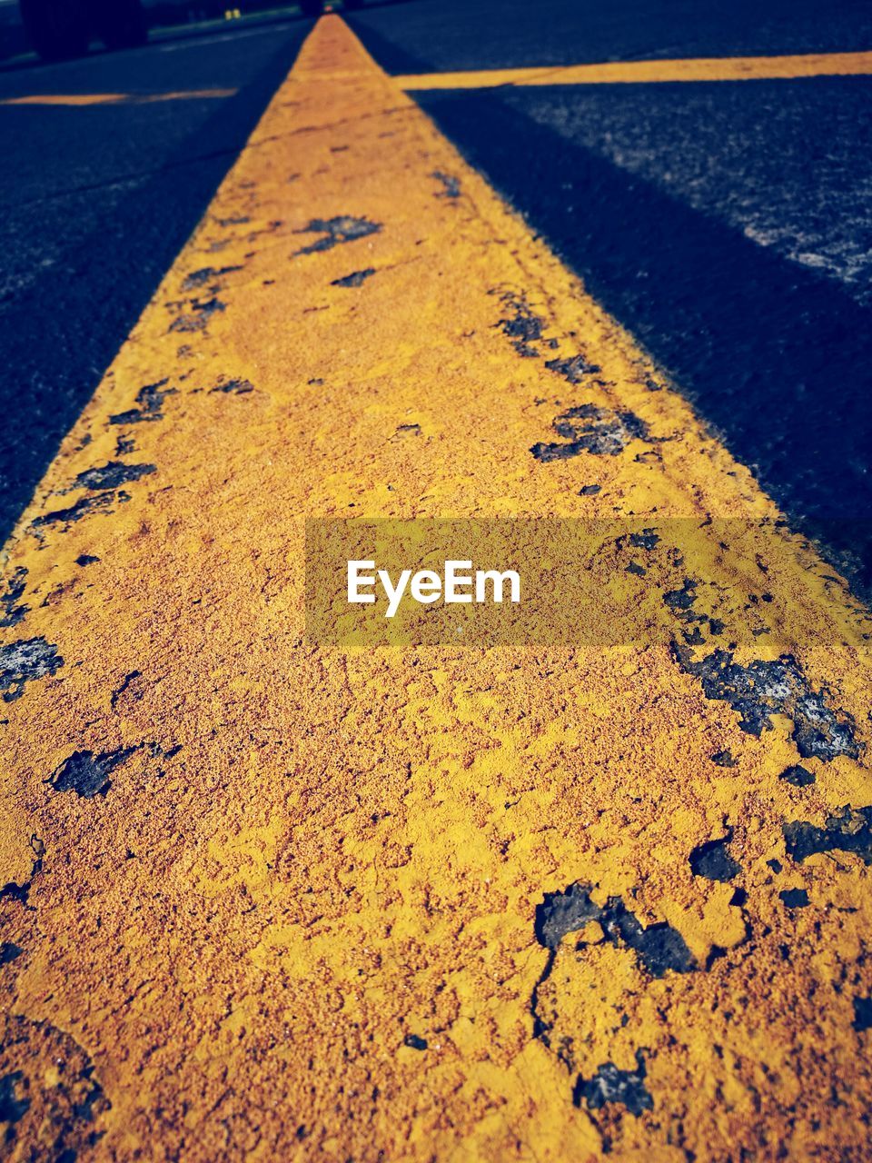 CLOSE-UP HIGH ANGLE VIEW OF YELLOW MARKING ON ROAD