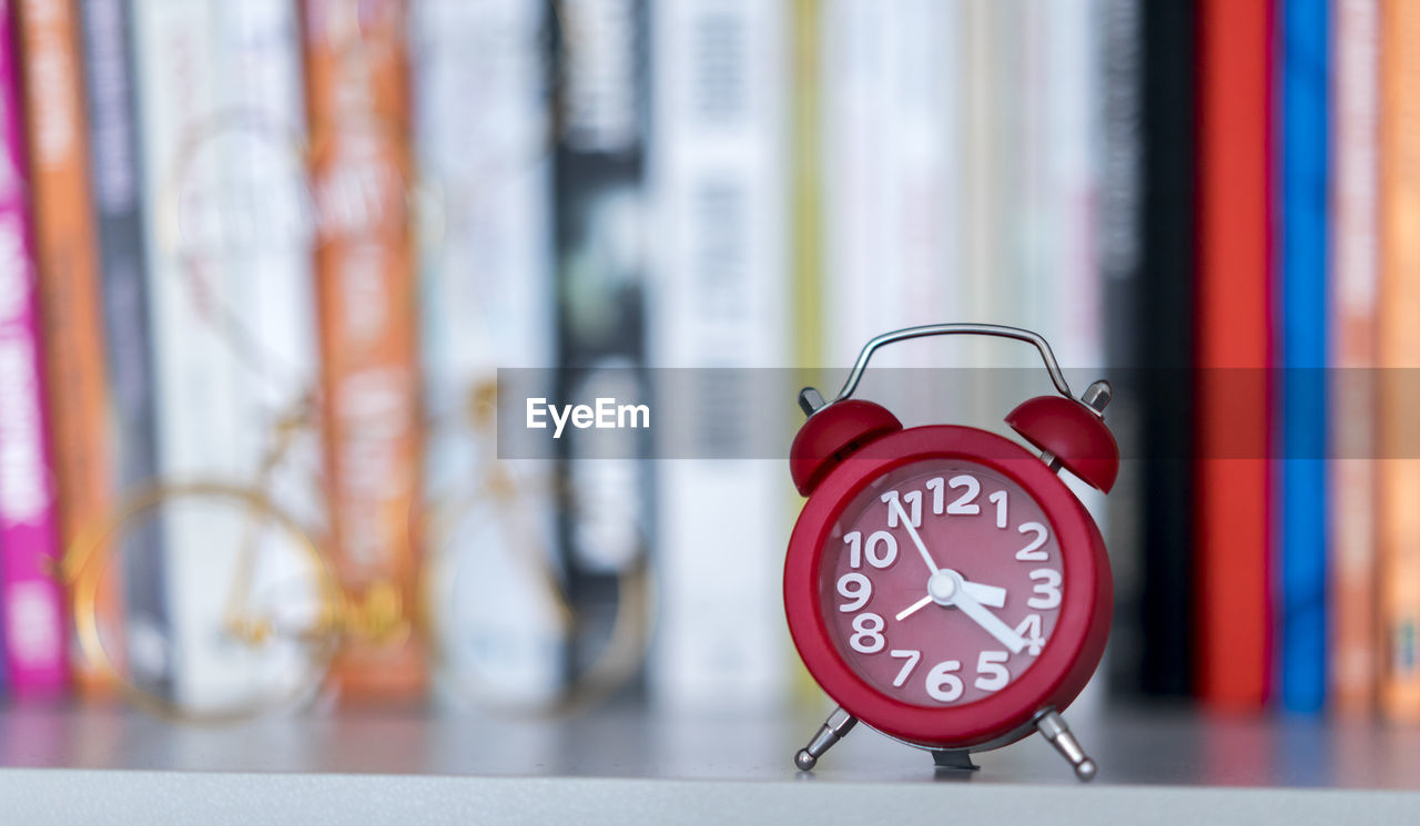 Close-up of alarm clock against books