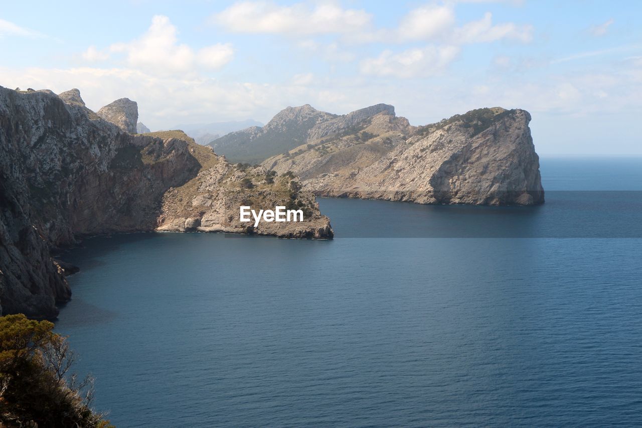 Scenic view of sea by mountains against sky