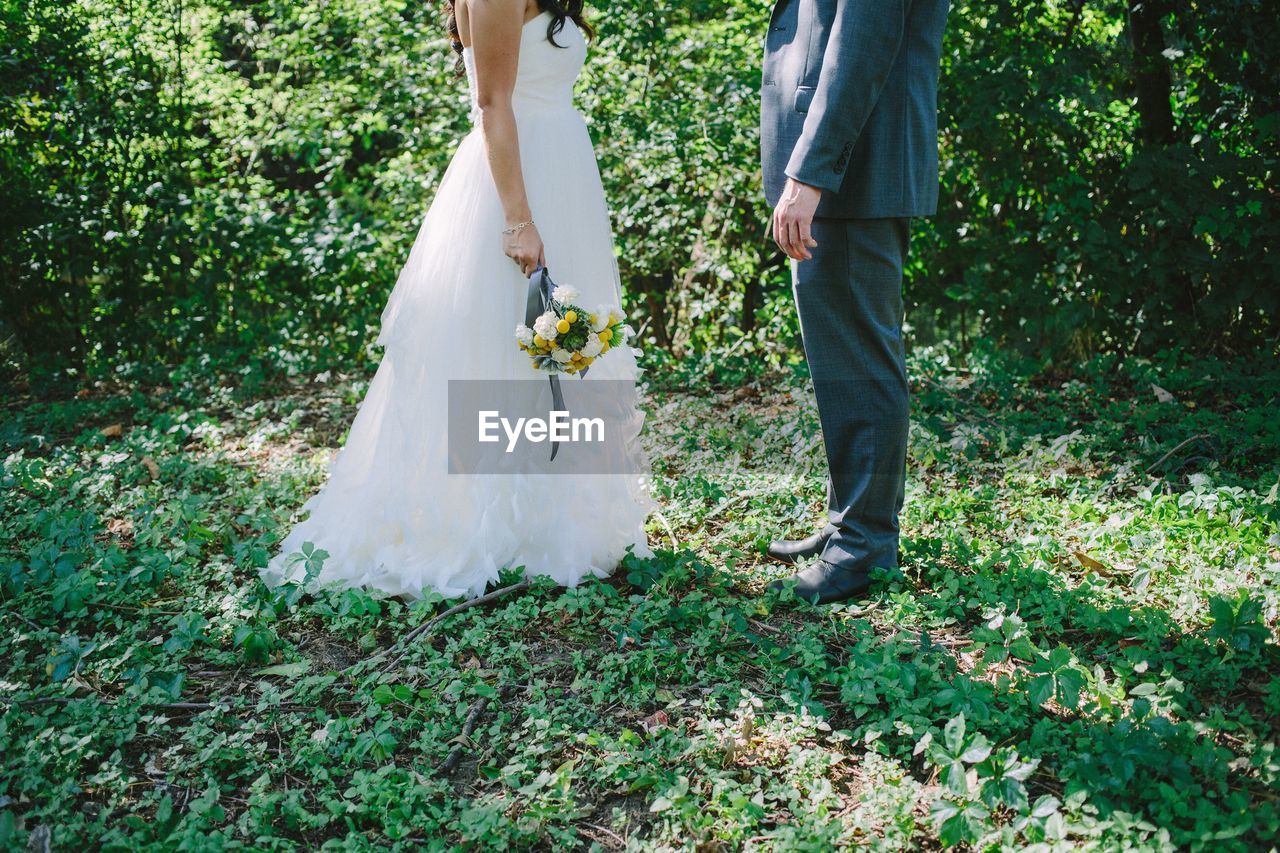 Low section of bride and groom standing on field