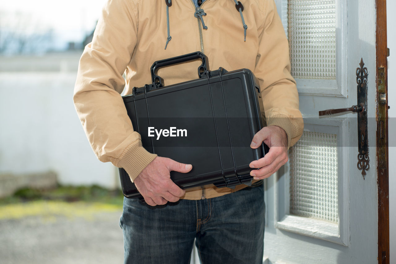 Midsection of man holding briefcase