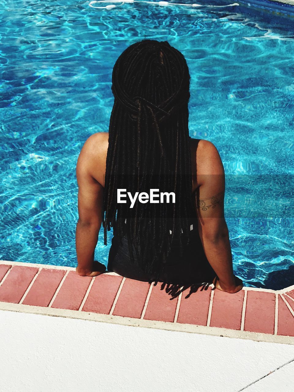 Rear view of woman with dreadlocks in swimming pool