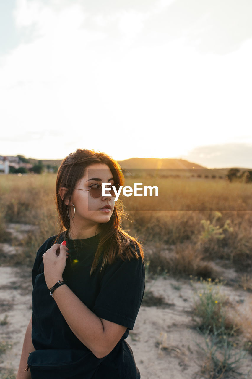 Teenager in sportswear and sunglasses at sunset in the countryside