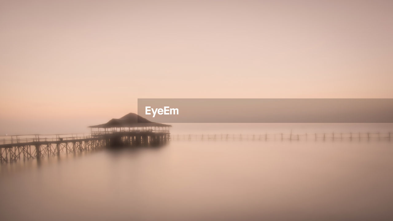 Joglo house with bridge on the misty beach, illuminated color image