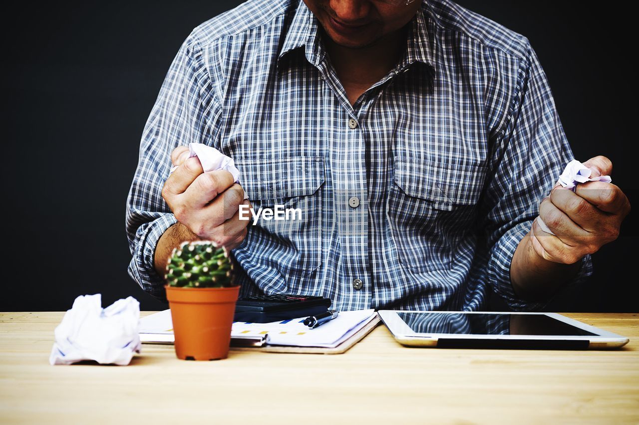 Midsection of businessman crumpling papers at desk in office