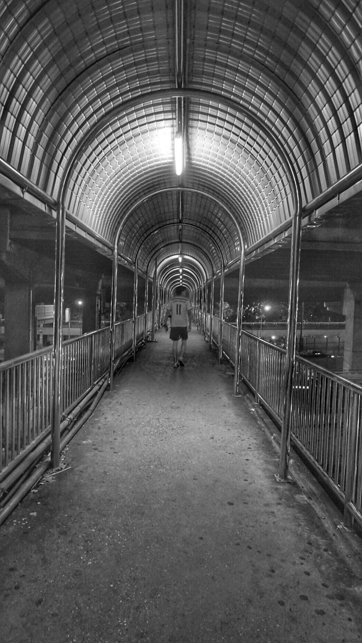 Full length rear view of man walking on illuminated walkway