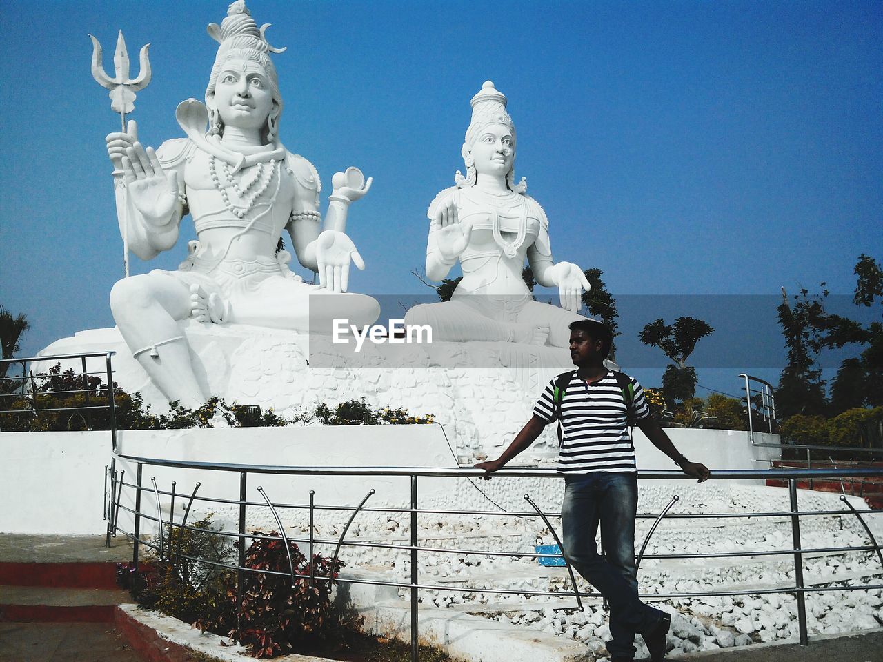 Man standing against statues and sky