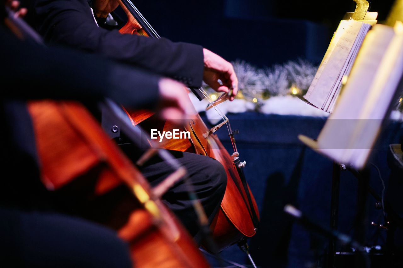 Midsection of musicians playing cello on stage