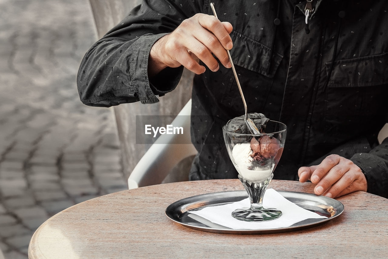 MIDSECTION OF PERSON POURING WINE IN WINEGLASS