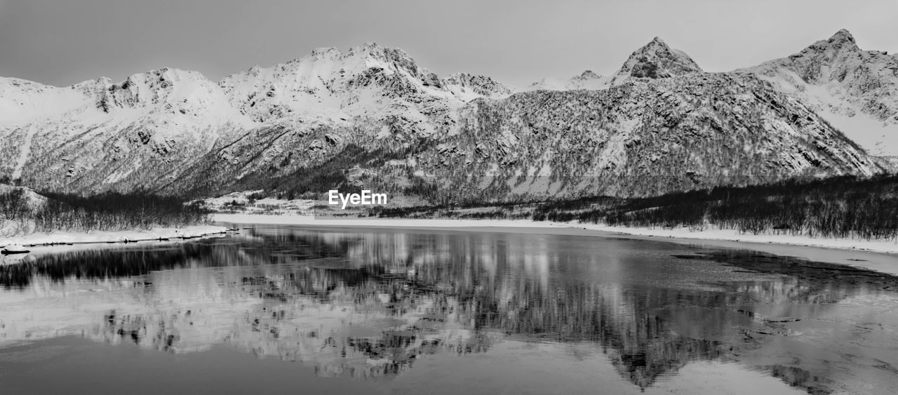 Scenic view of snowcapped mountains by lake against sky during winter