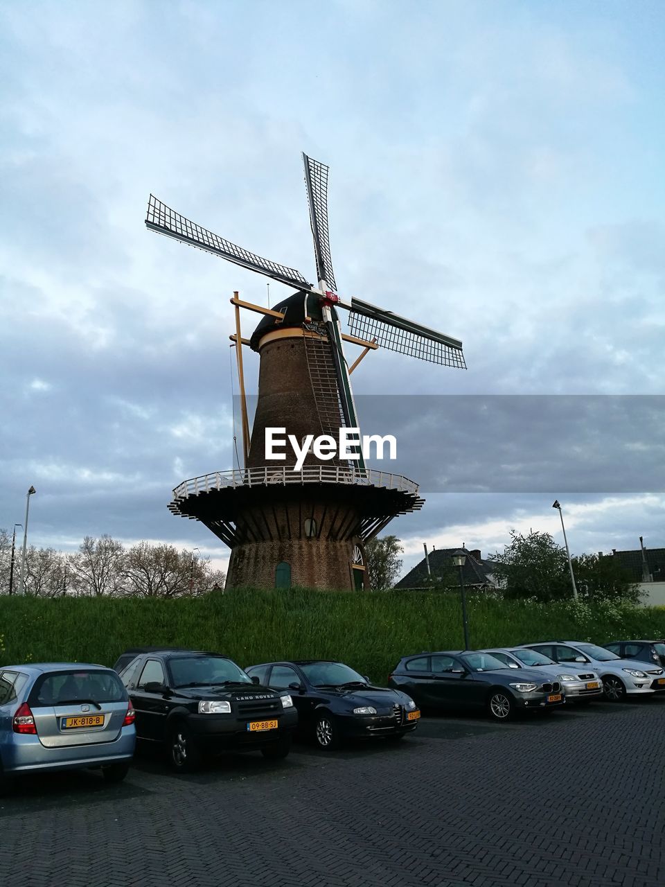 TRADITIONAL WINDMILL BY CARS AGAINST SKY