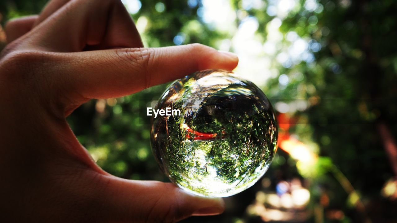 CLOSE-UP OF HUMAN HAND HOLDING GLASS OF CRYSTAL BALL