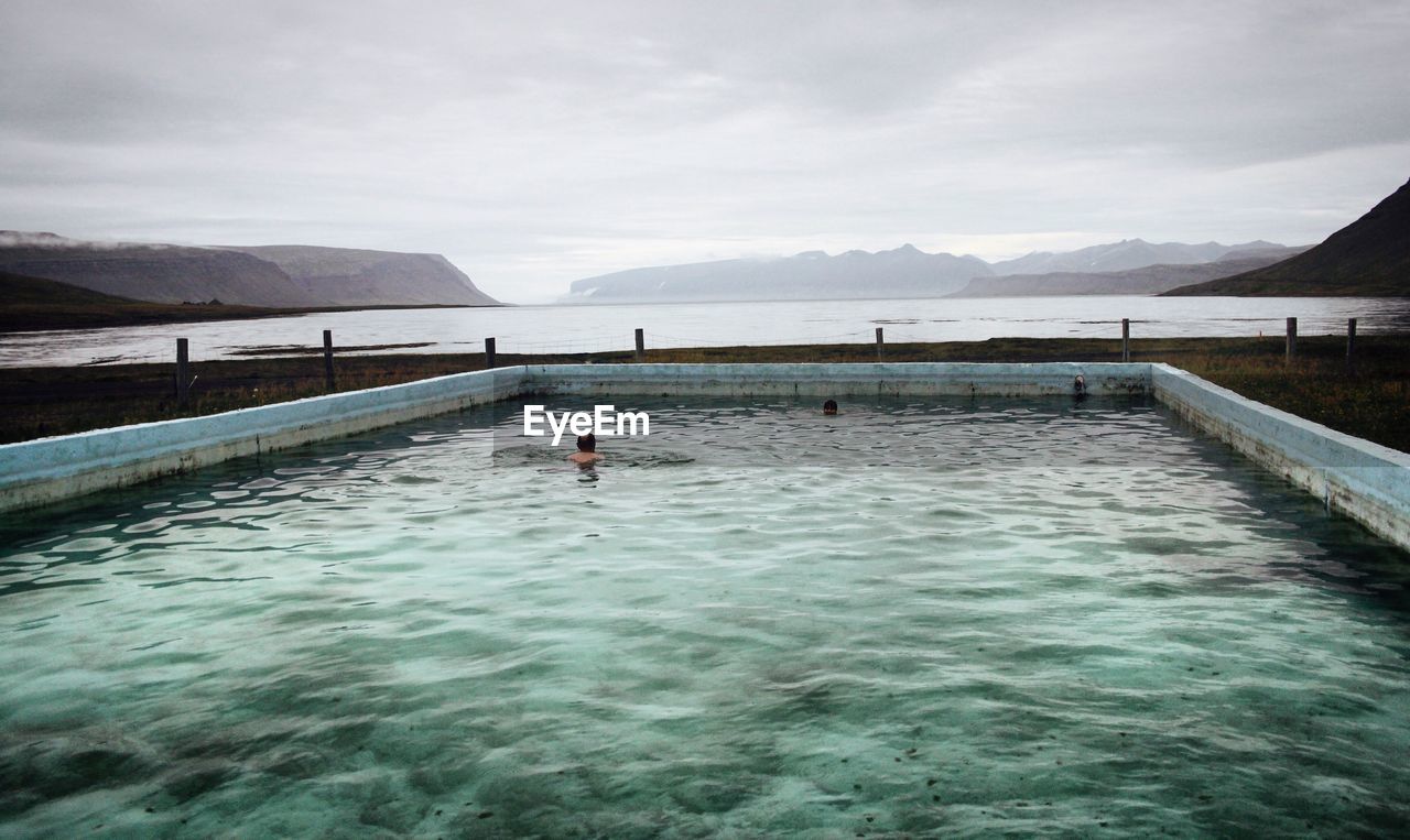 View of swimming pool by sea against mountains
