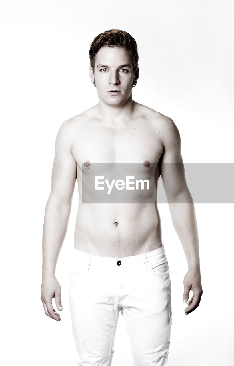Portrait of shirtless man standing against white background