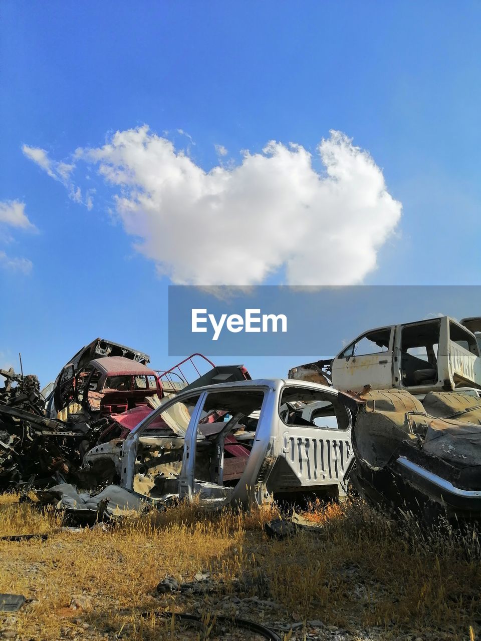 Abandoned cars on field against sky