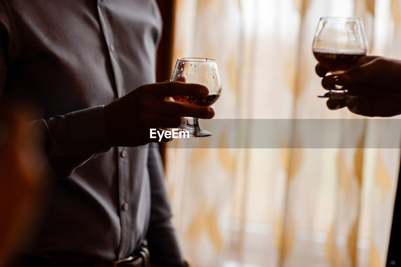 Men with a friend standing by the window. hold in the hands of glasses of whiskey.