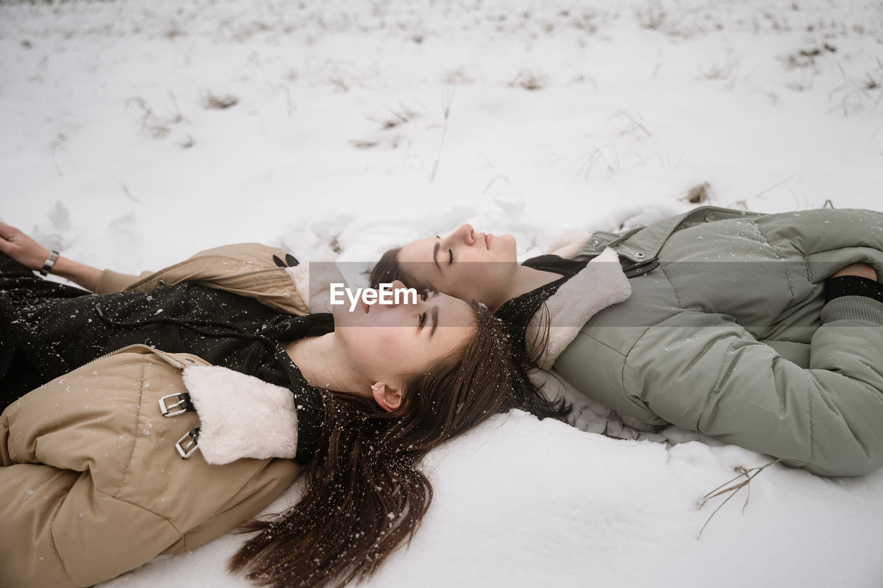 Young women lying on snow outdoors