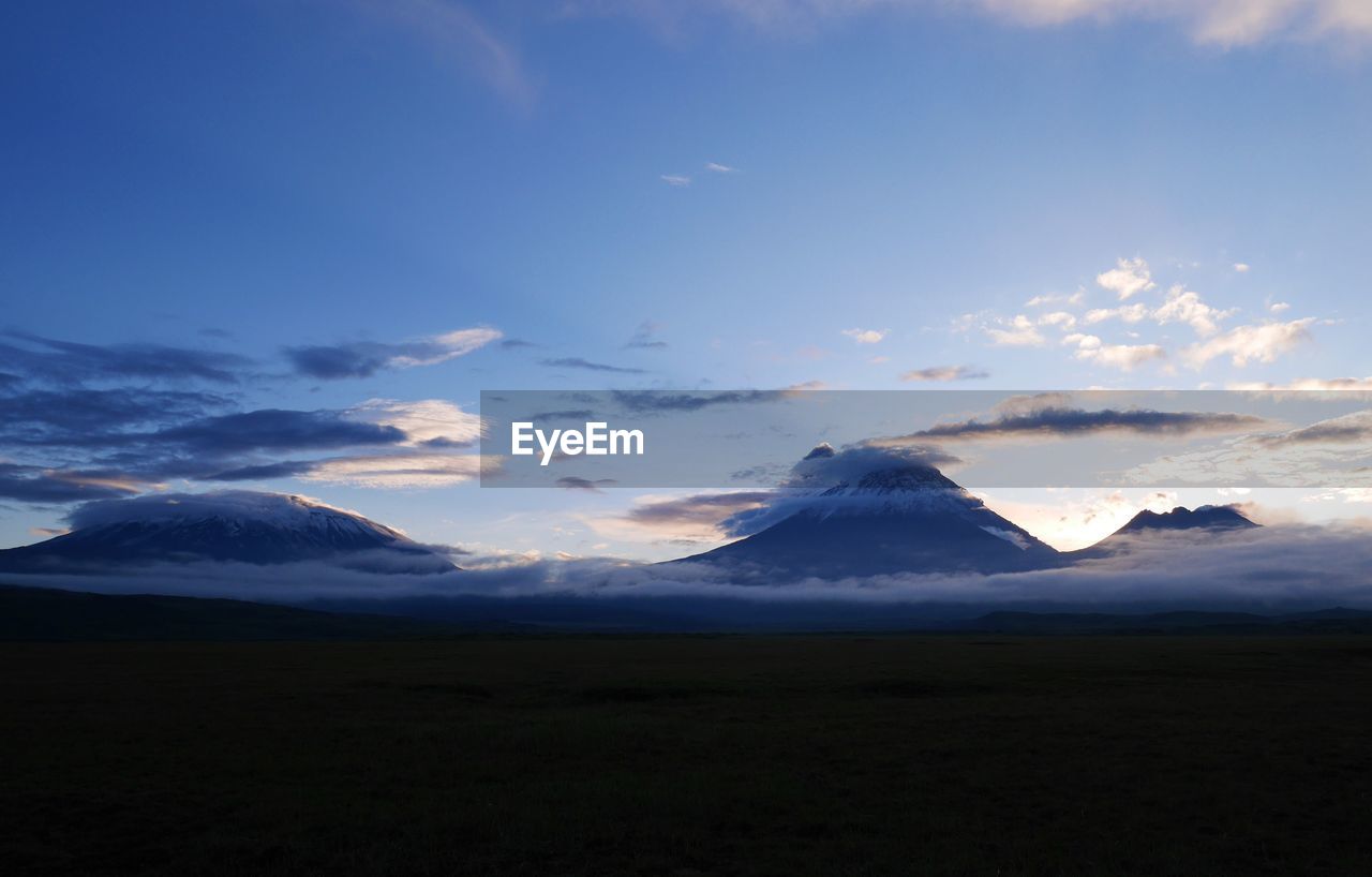 Scenic view of mountains covered with clouds against sky at dusk