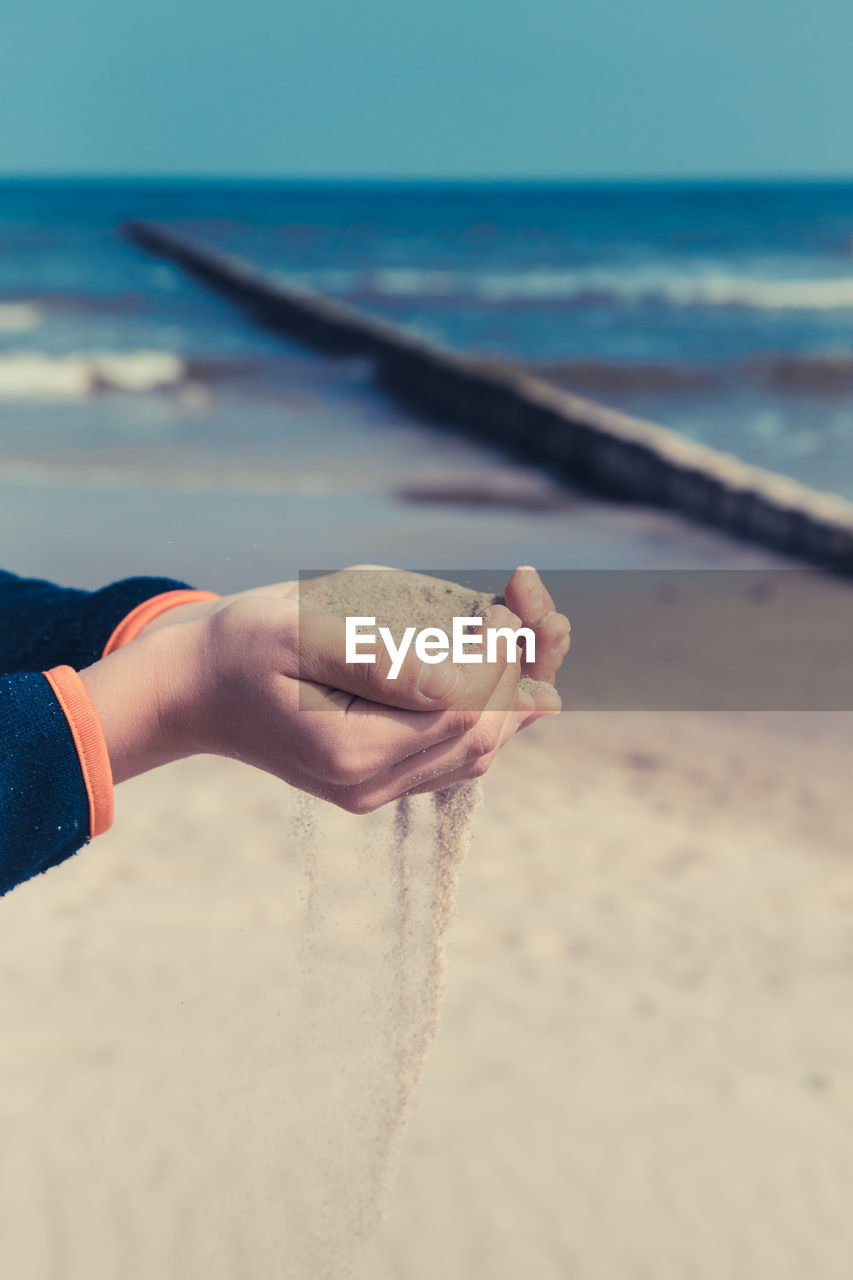 MIDSECTION OF PERSON HAND HOLDING SAND