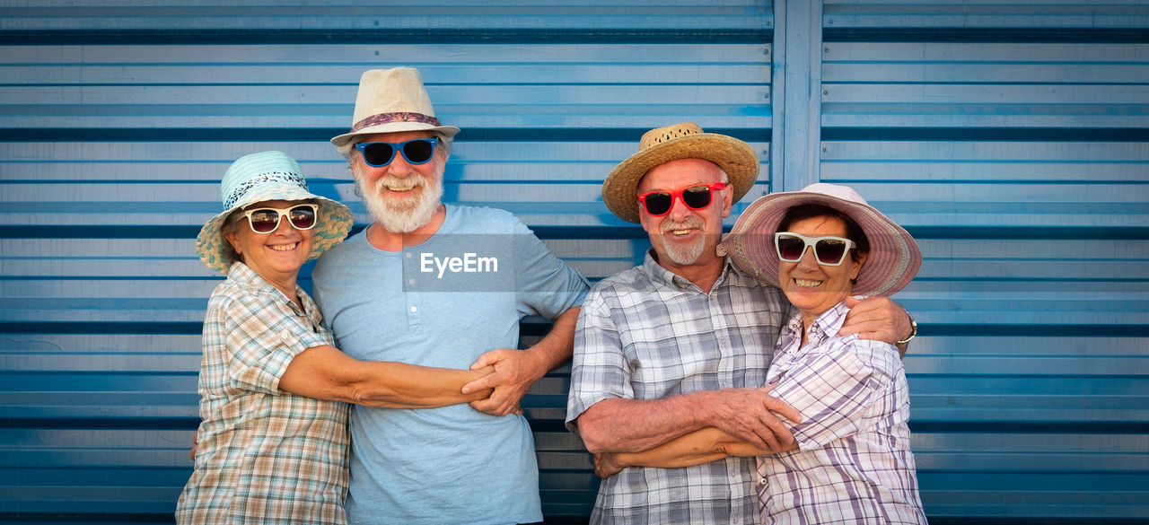 Portrait of smiling senior couples standing with arms around against shutter