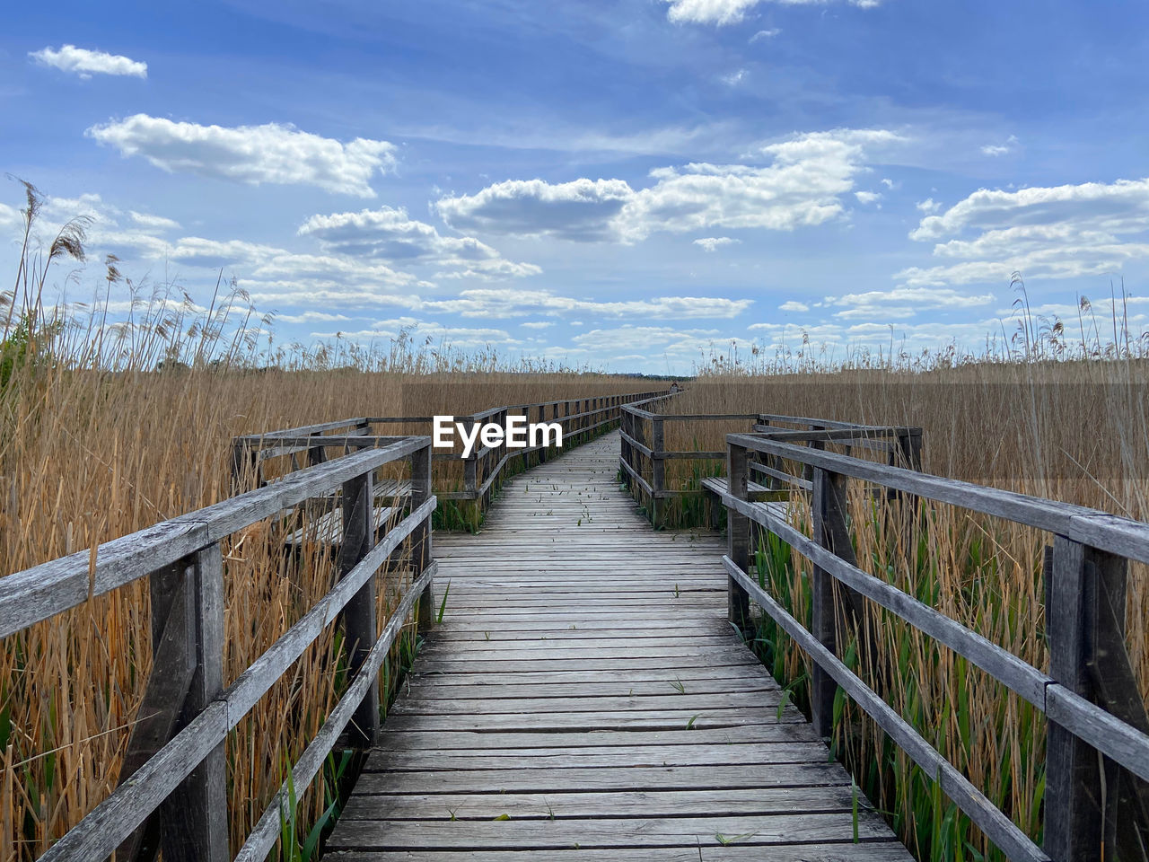 Wooden footbridge against sky