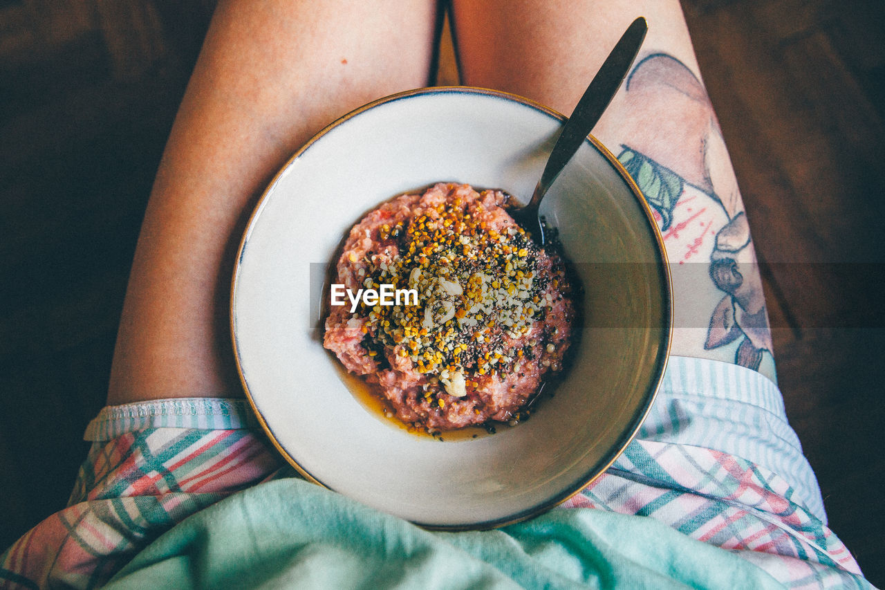 Low section of person with bowl of porridge on lap