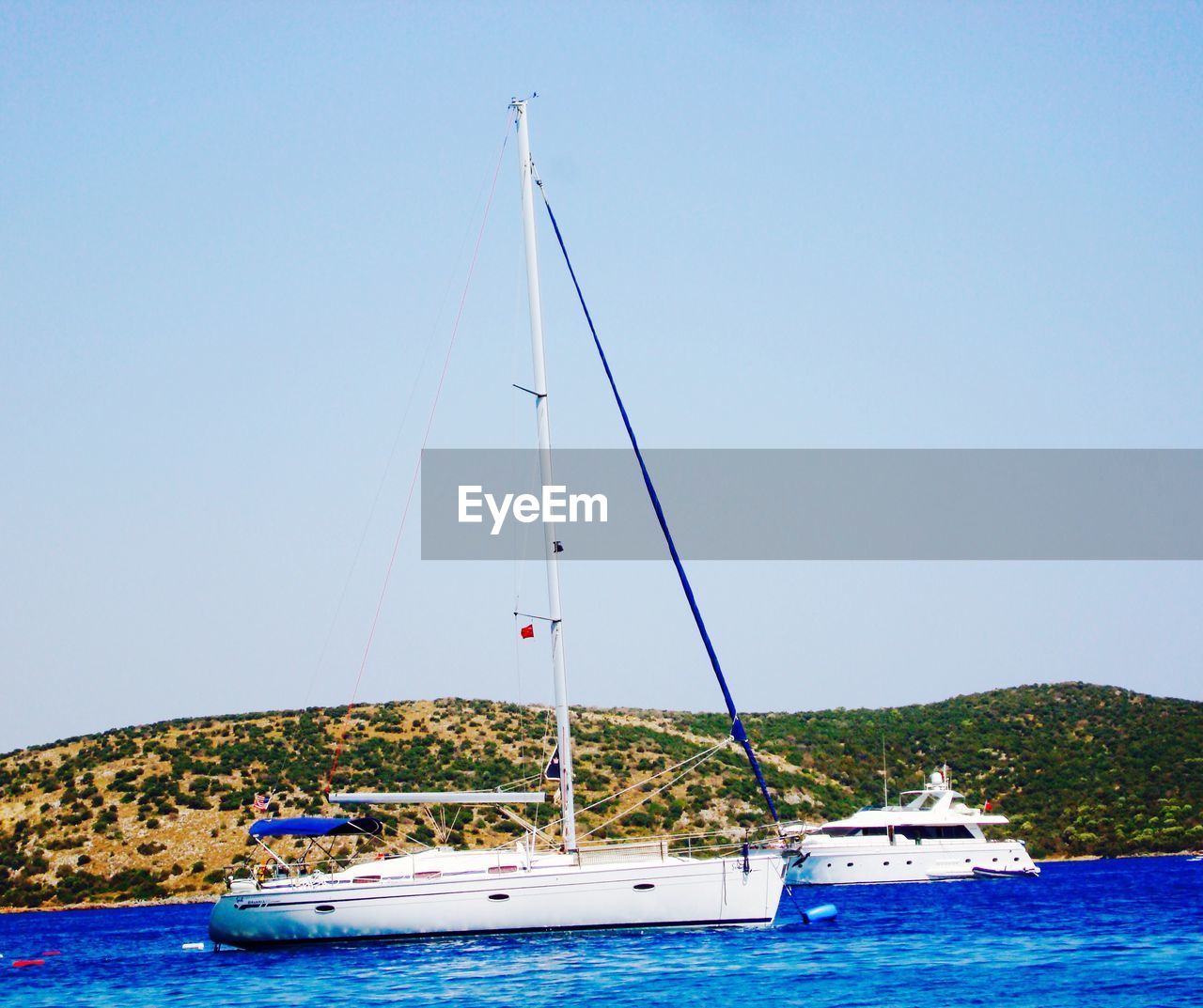 Boats sailing on sea against clear sky